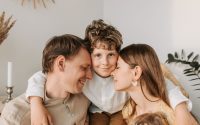 A joyful family moment with parents and their son embracing indoors.